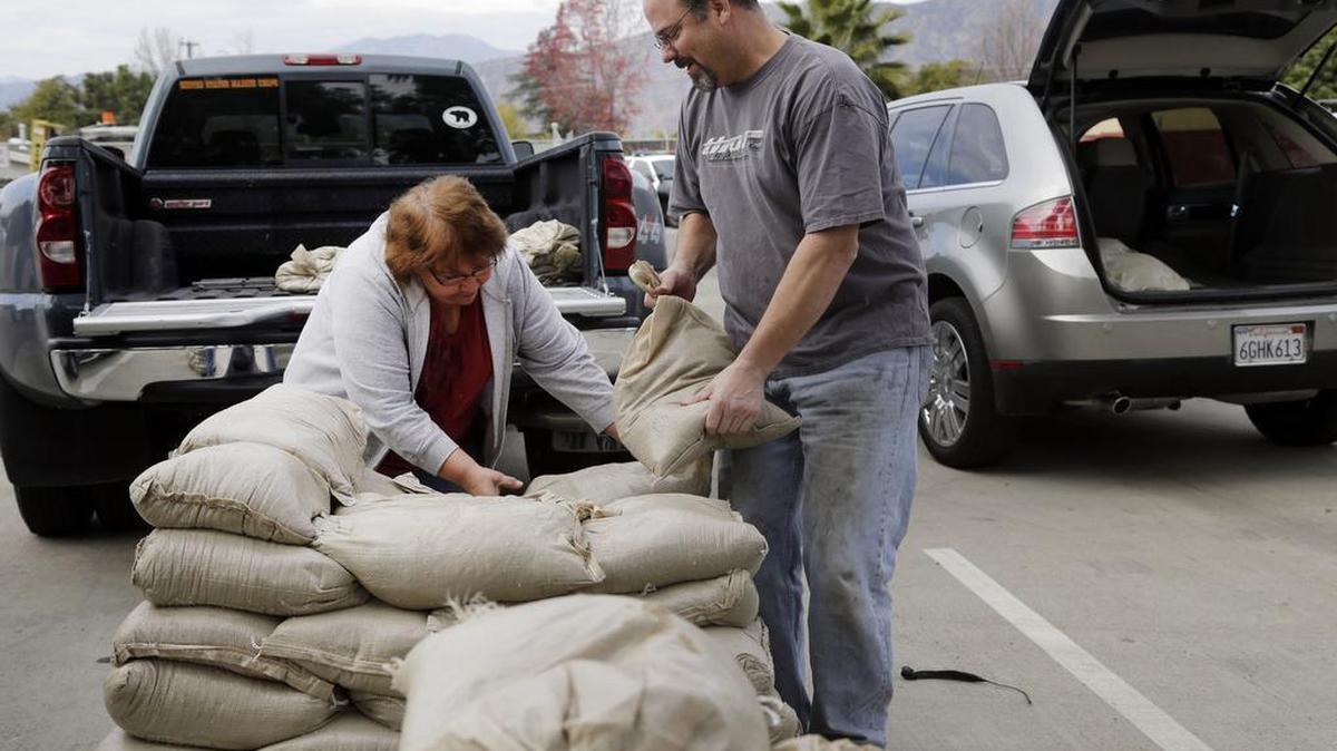 Residents Trina Gonzalez, left, and Todd Peterson stockpile sandbags to protect their homes from the rain in Glendora, Calif., on Monday. After all the talk, El Nino storms have finally lined up over the Pacific and started soaking drought-parched California with rain expected to last for most of the next two weeks, forecasters said Monday.
