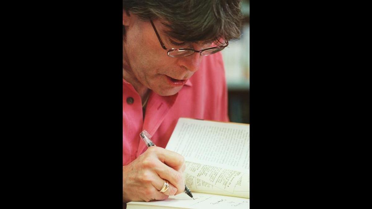 Stephen King signs a copy of his book, “On Writing: A Memoir of the Craft,” for a fan at BookMarc bookstore in downtown Bangor, Maine, Wednesday, Oct. 25, 2000.
