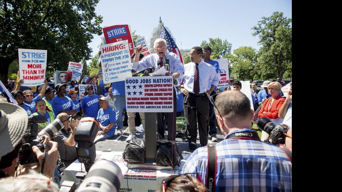
Democratic presidential candidate Sen. Bernie Sanders, I-Vt., joined by Rep. Keith Ellison, D-Minn., at right, and federal contract workers, speaks during a rally on Capitol Hill in Washington, Wednesday, July 22, 2015, to push for a raise to the minimum wage to $15 an hour. 
