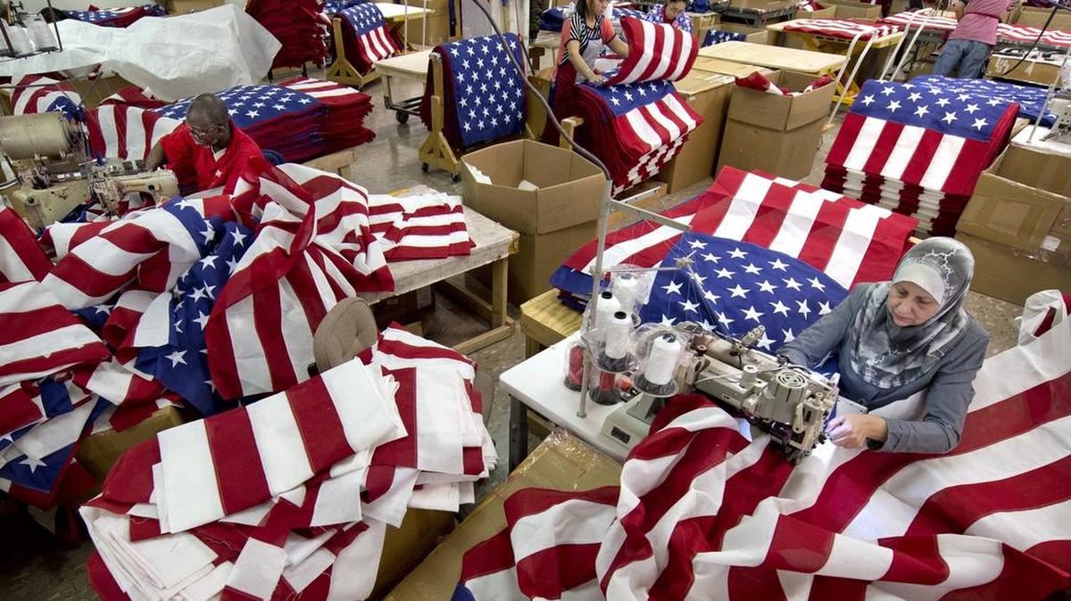 Amadou Sy (left) from Mauritania and Nuha Mahdi (right) from Iraq were among those making flags Thursday at Allied Materials & Equipment, 1420 Kansas Ave. Workers from 13 nations sew, cut and pack U.S. flags at the plant in east Kansas City.