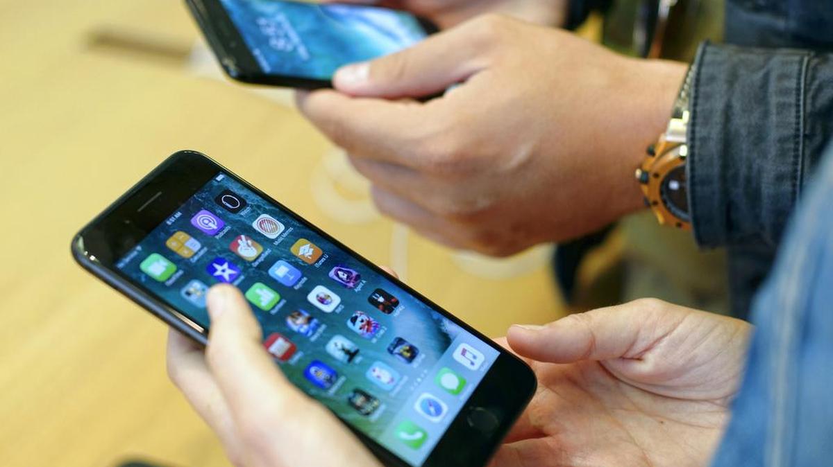 Customers check out the new Apple iPhone 7 at the Apple Store at the Grove in Los Angeles on Friday, Sept. 16, 2016. A satirical video purporting to show that drilling a hole into the iPhone 7 will create a headphone jack, which the device lacks, has tricked some users into ruining their new phones.