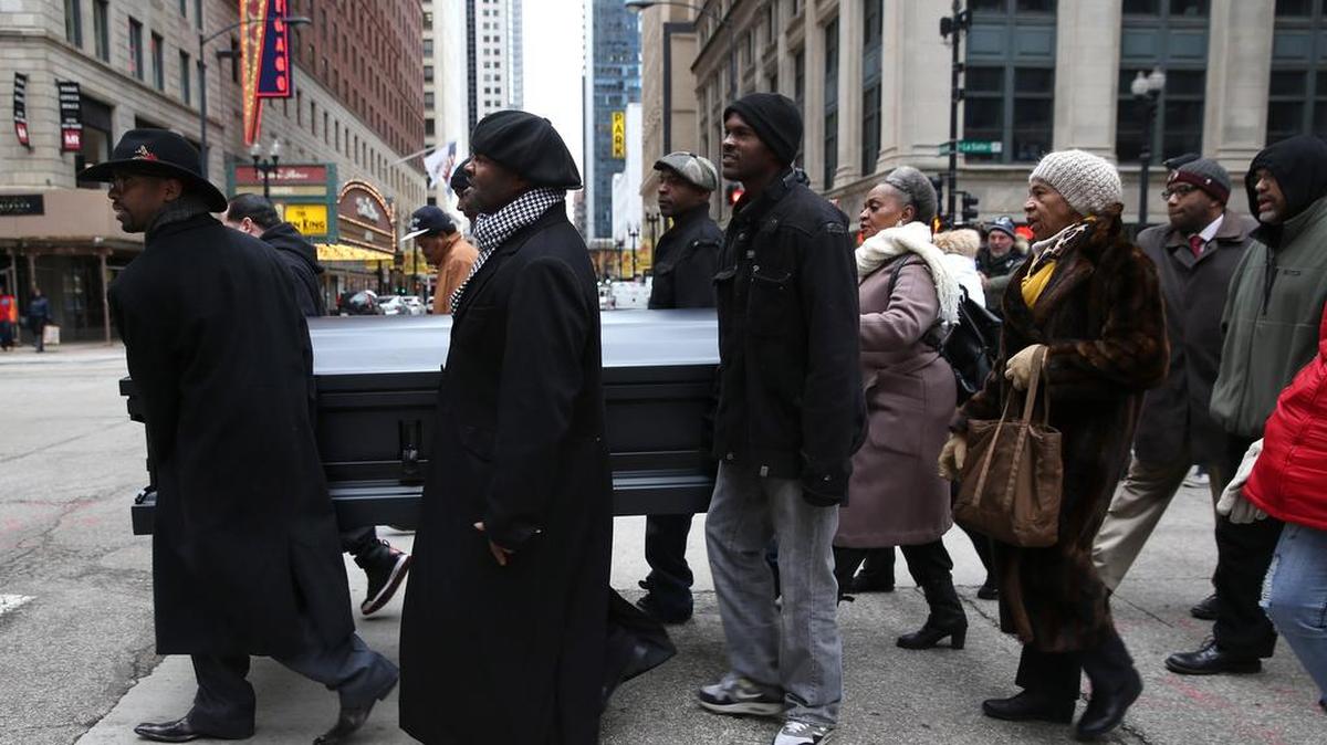 Community activist James Tiller, left, and a small group of protesters carry a coffin toward Chicago's City Hall and walk around the building, protesting the killing of Laquan McDonald, on Nov. 28, 2015.