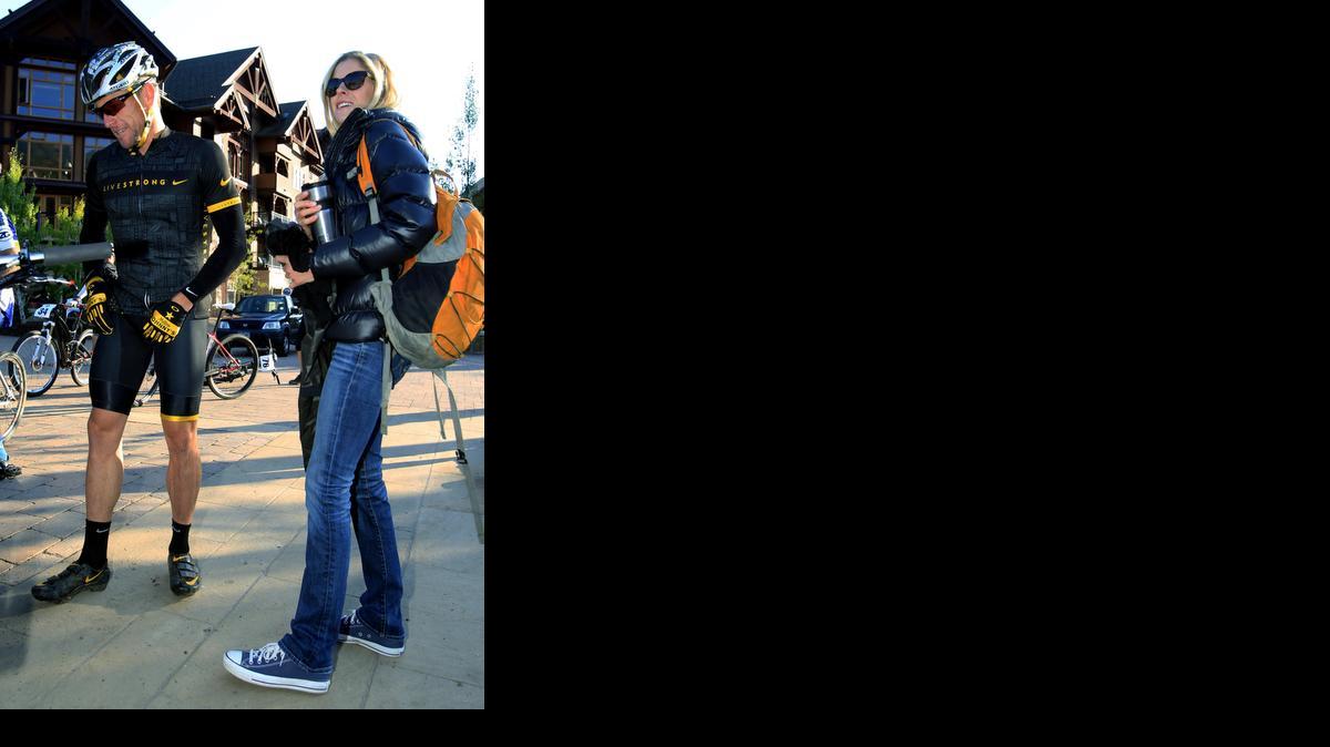 
Lance Armstrong, left, prepares to take part in the Power of Four mountain bicycle race, as his girlfriend, Anna Hansen, looks on, in Snowmass Village, Colo., Aug. 25, 2012. Authorities say the disgraced cyclist hit two parked cars after a night of partying in Aspen but agreed to let his girlfriend take the blame to avoid national attention. 
