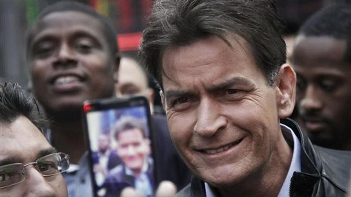 In this Jan. 14, 2013, photo, actor Charlie Sheen is mobbed for autographs and photos as he makes his way through Times Square in New York.
