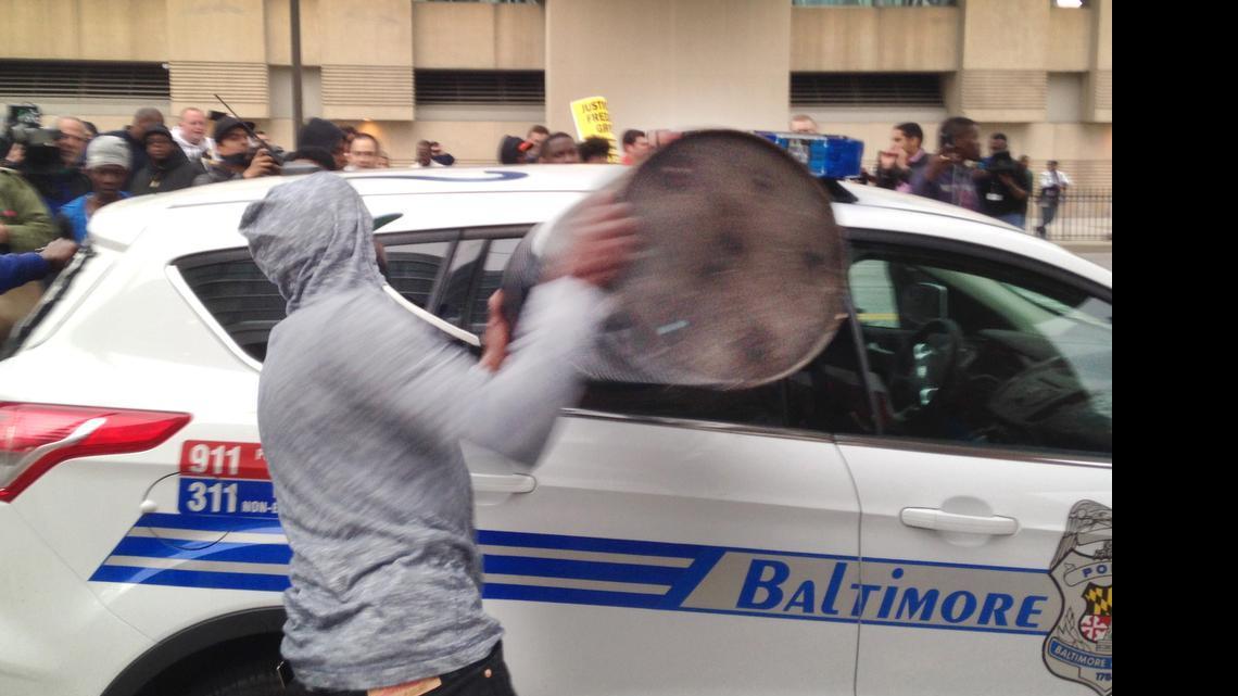 
A protestor smashes the window of a Baltimore police vehicle on Saturday, April 25, 2015, as protests continue in the wake of Freddie Gray's death while in police custody. 
