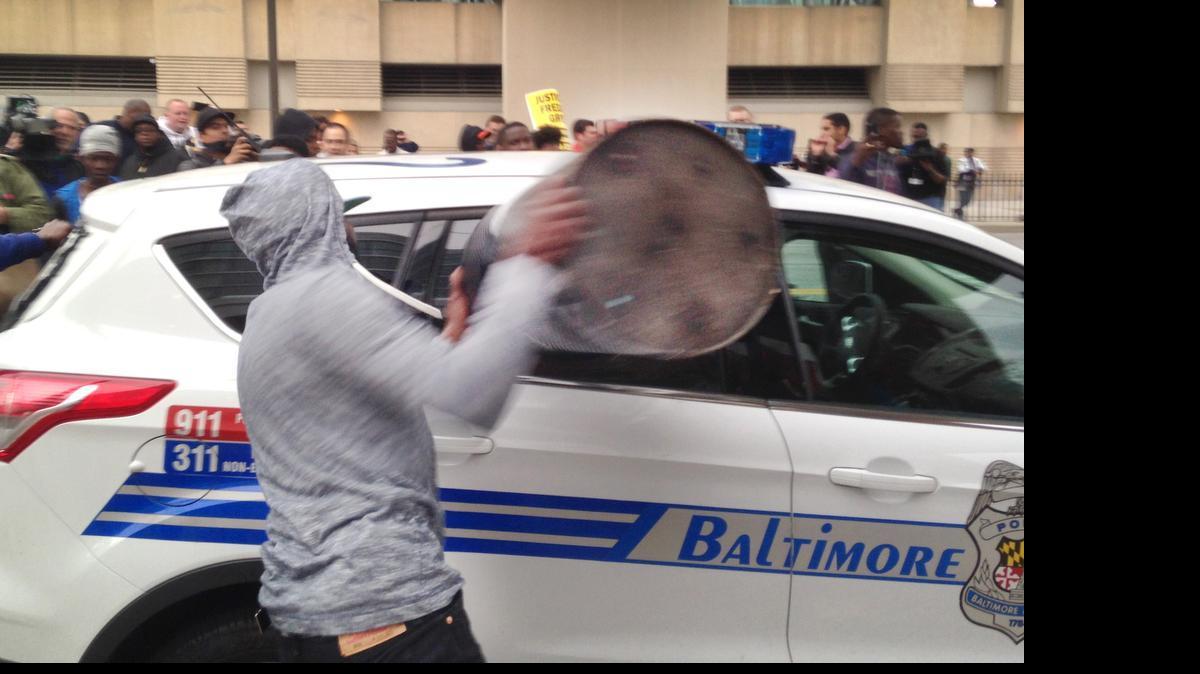 
A protestor smashes the window of a Baltimore police vehicle on Saturday, April 25, 2015, as protests continue in the wake of Freddie Gray's death while in police custody. 
