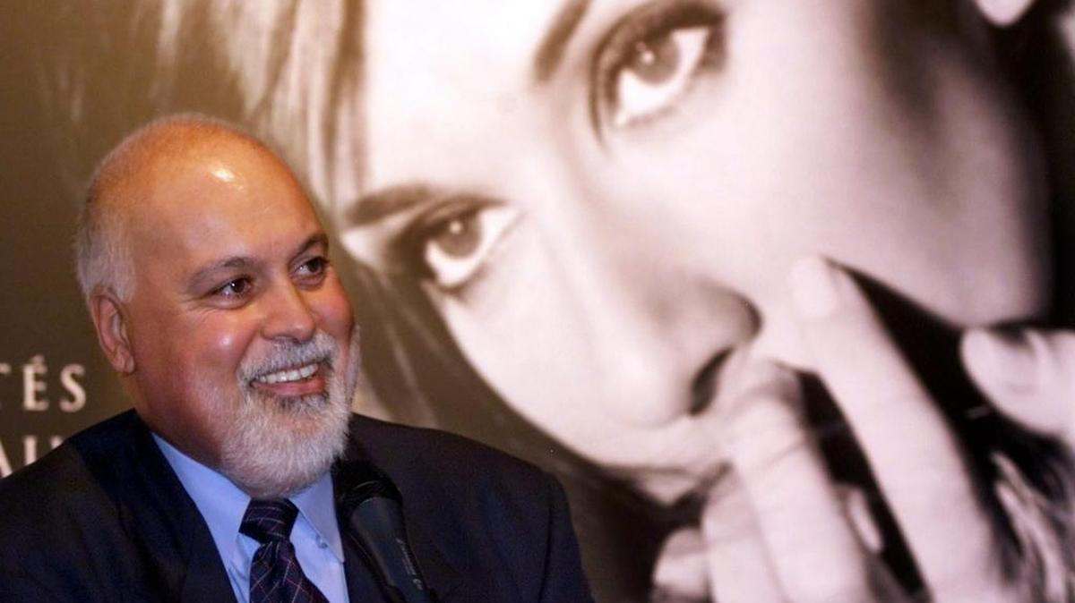 Rene Angelil stands in front of a giant photograph of his wife, singer Celine Dion, during a news conference in Montreal on Sept. 8, 1999 file photo.