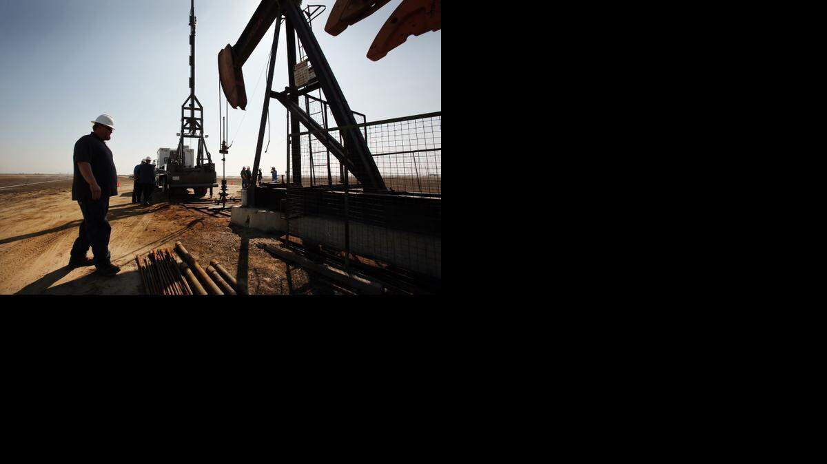 
Jonathan Wilcox, left, a field manager watches as Aaron Kent, a wireline operator for Canary, LLC, works on a slick line at an oil rig pump jack site in the oil fields near Bakersfield, California, on March 13, 2013. 
