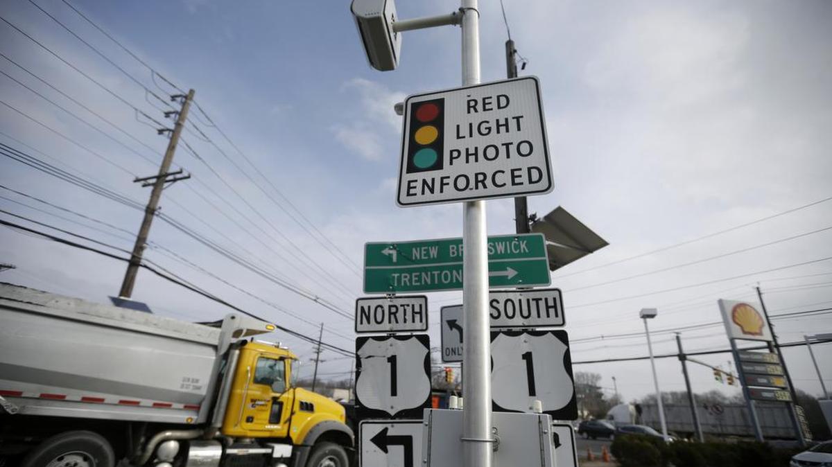 A truck passes a red light photo enforcement sign placed below a red light camera in Lawrence Township, N.J., on Dec. 16, 2014. Red-light cameras are widely hated, but a new study says getting rid of them can have fatal consequences. Traffic deaths from red-light-running crashes go up by nearly a third after cities turn off cameras designed to catch motorists in the act, according to a study by the Insurance Institute for Highway Safety. The institute is funded by auto insurers.