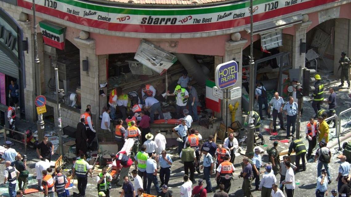 Police and medics surround the scene of a bomb explosion in a restaurant downtown Jerusalem Thursday, Aug. 9, 2001. A bomb exploded in the pizza restaurant Sbarro at lunchtime on Thursday, killing at least 13 people and wounding more than 70.