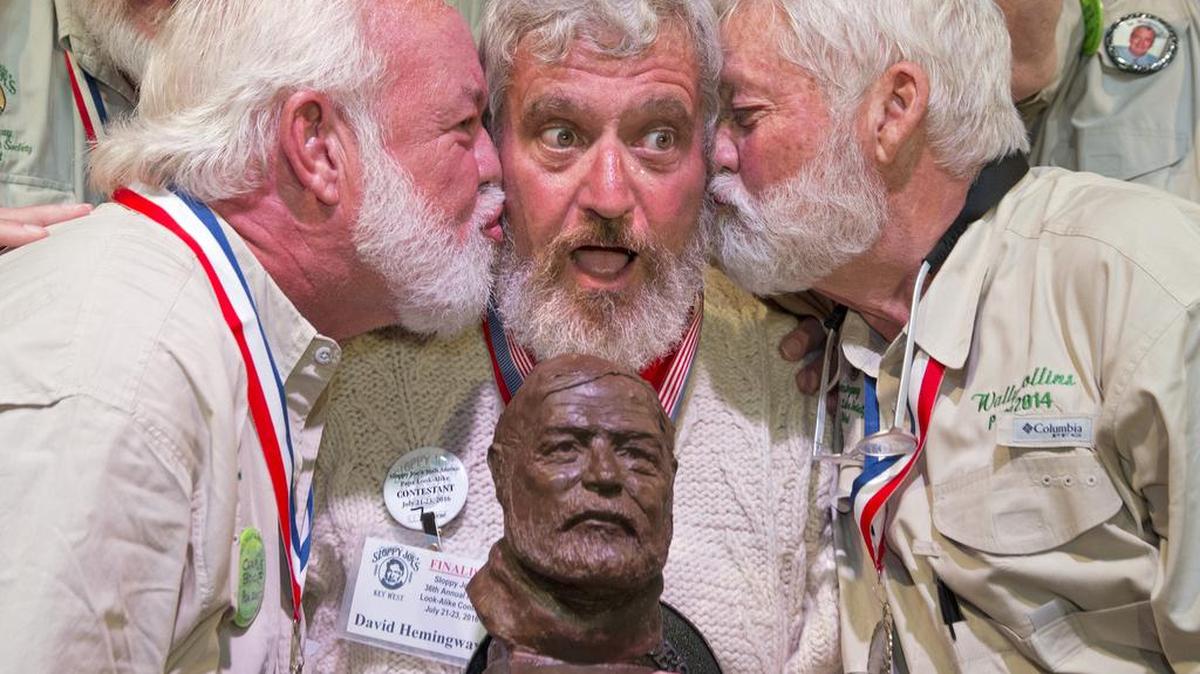 Dave Hemingway, center, receives smooches from Charlie Boise, left, and Wally Collins, right, after Hemingway won the 2016 Ernest “Papa” Hemingway Look-Alike Contest in Key West, Fla. Success for Dave Hemingway came on the Macon, N.C., resident’s seventh attempt to win the coveted title at Sloppy Joe’s Bar. Dave Hemingway is not related to Ernest Hemingway who lived and wrote in Key West in the 1930s.