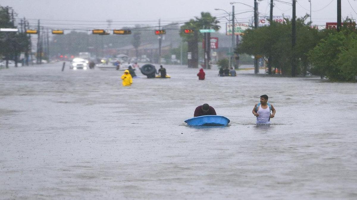 People walk back in to help others evacuate their homes near south Beltway 8 up Telephone Rd., Tuesday in Houston.