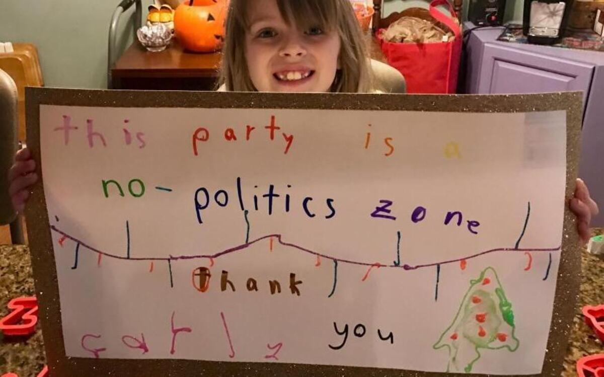 Eight-year-old Carly Barr holds the sign she made at her mom Jennifer’s suggestion, banning political discussions at their Christmas kick-off party. It worked!