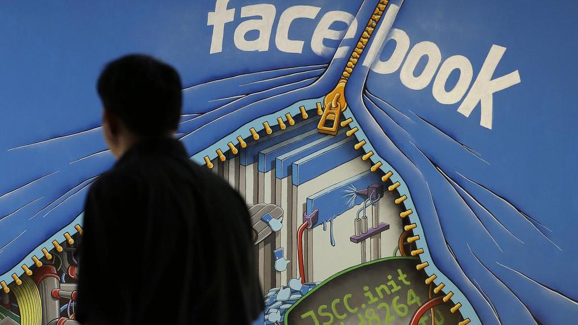 A man walks past a mural in an office on the Facebook campus in Menlo Park, Calif., in 2014.