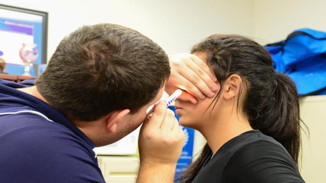 Danielle Guillama, 16, is checked for signs of a concussion after a hit to the head during a basketball game at Miami Palmetto High. Athletic trainer intern John Barrass, 21, concluded Guillama had a concussion.