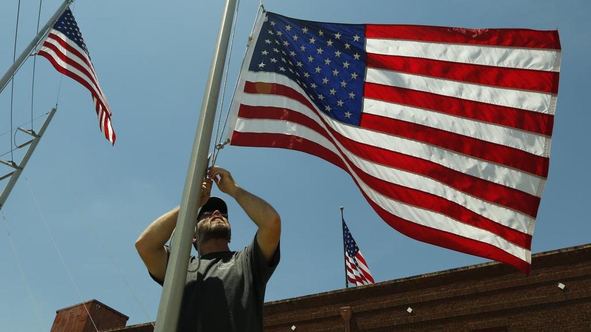 Perry Noblett of Lone Star Banners and Flags makes adjustments to flags outside their business in south Fort Worth.