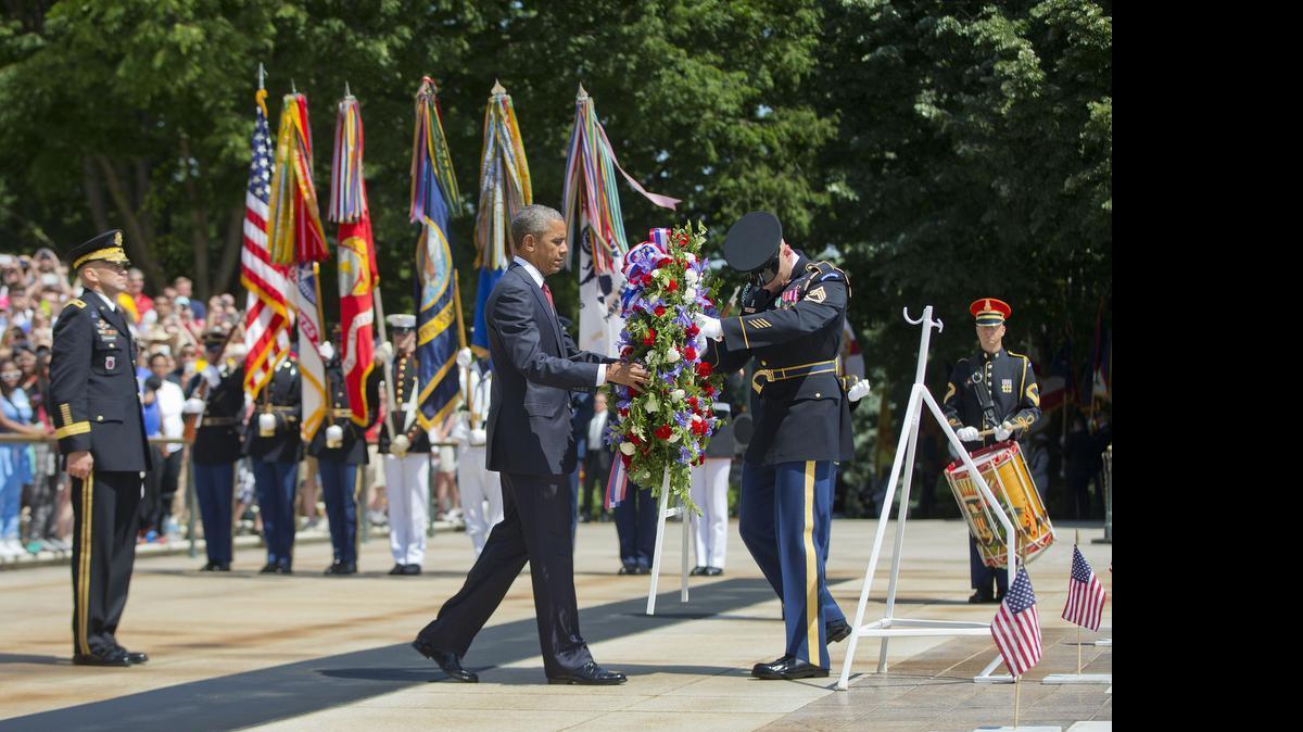 
President Barack Obama, accompanied by Maj. Gen. Jeffrey S. Buchanan, left, Commander of the U.S. Army Military District of Washington, and the with the aid of Sgt. 1st Class John C. Wirth, lays a wreath at the Tomb of the Unknowns, on Memorial Day, Monday, May 25, 2015, at Arlington National Cemetery in Arlington, Va. 
