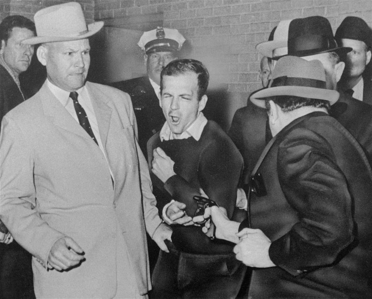 Lee Harvey Oswald, assassin of President John F. Kennedy, reacts as Dallas night club owner Jack Ruby, foreground, shoots at him from point blank range in a corridor of Dallas police headquarters, Nov. 24, 1963. At left is Detective Jim Leavelle.