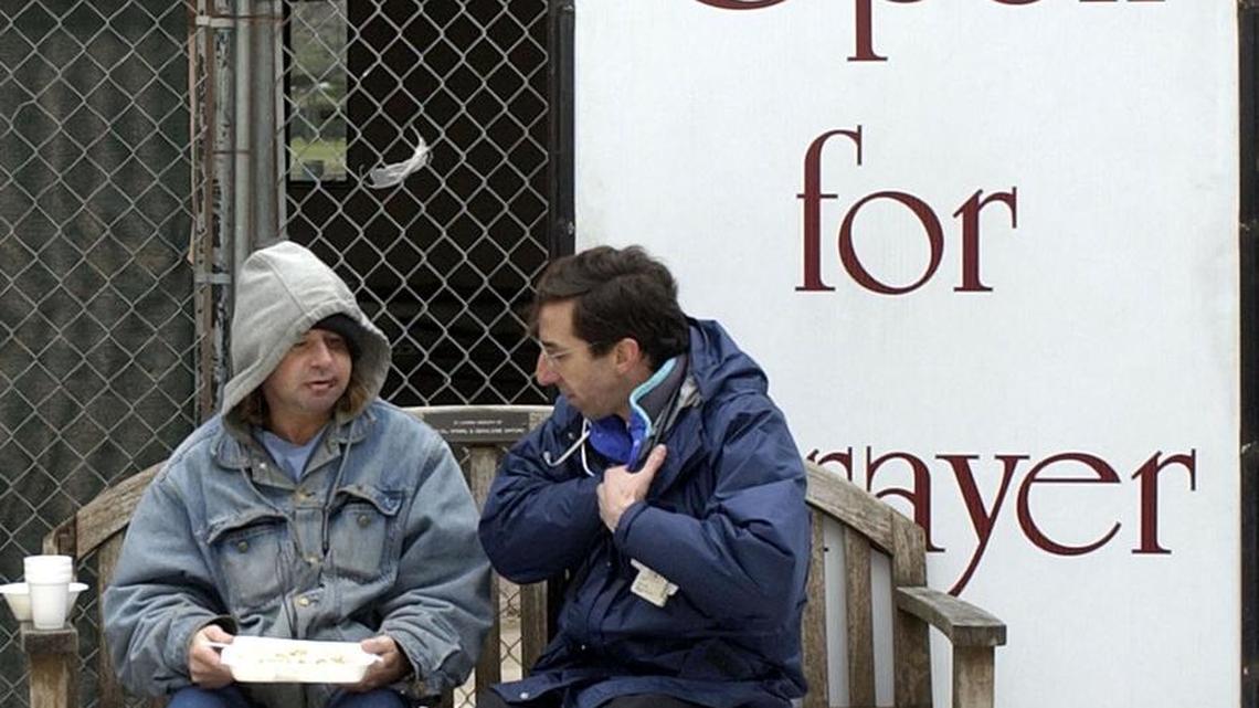 Rodney Burger, left, eats his free breakfast in a Houston churchyard as he consults with Dr. David Buck, right, president and chief medical officer for Healthcare for the Homeless-Houston, Thursday, Feb. 12, 2004, in Houston. Buck works with Project Access, a free service to give some of the city's 12,000 homeless a better chance of making needed trips to clinics, shelters and social service agencies.