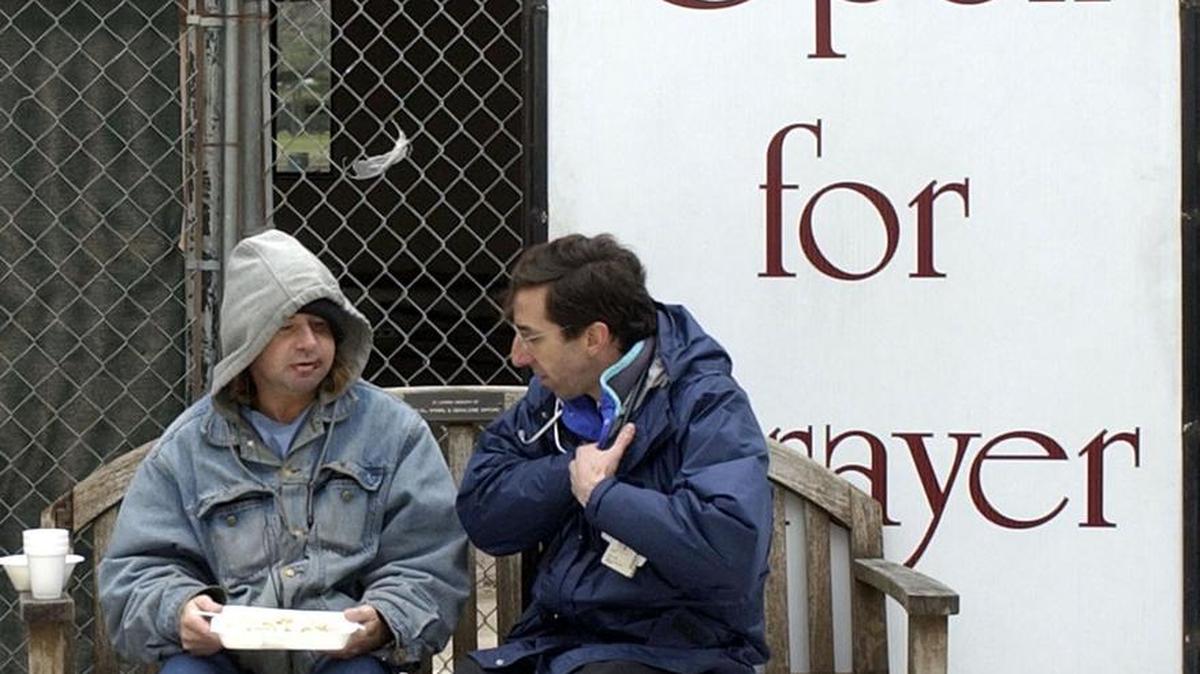 Rodney Burger, left, eats his free breakfast in a Houston churchyard as he consults with Dr. David Buck, right, president and chief medical officer for Healthcare for the Homeless-Houston, Thursday, Feb. 12, 2004, in Houston. Buck works with Project Access, a free service to give some of the city's 12,000 homeless a better chance of making needed trips to clinics, shelters and social service agencies.