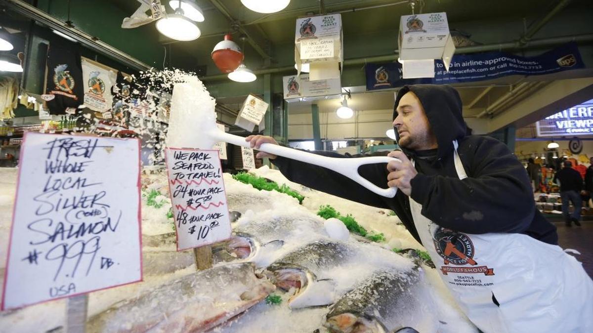 Pike Place Fish Market fishmonger Erik Espinoza shovels ice onto fresh fish at the Pike Place Market in Seattle, Wash. on Oct. 3, 2013.