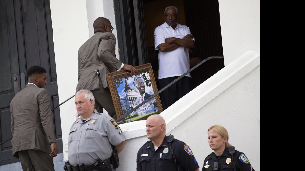 
A portrait of Sen. Clementa Pinckney, one of the nine killed in last week's shooting, is carried in for his wake at Emanuel AME Church, Thursday, June 25, 2015, in Charleston, S.C. The first funerals of some of those slain began Thursday at nearby churches with a viewing for Pinckney inside Emanuel on Thursday evening. President Barack Obama will deliver the eulogy at Pinckney's funeral Friday at a nearby college arena. 
