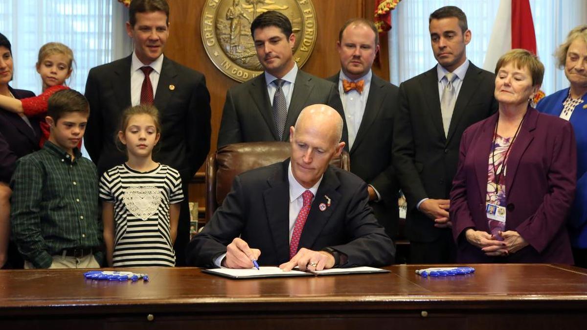Florida Gov. Rick Scott, center, signs the children with special abilities bills in his office at the state Capitol as legislators with their families look on, Thursday, Jan. 21, 2016, in Tallahassee, Fla. On Friday, Jan. 22, 2016, he listened to those who have been dubbed “The White House Boys,” childhood residents of the state-run Arthur G. Dozier School for Boys outside Marianna, Fla., so named for the infamous detention building where they say they endured horrific beatings and torture.