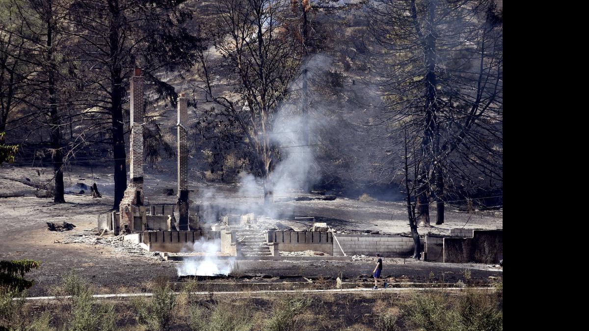 
The foundation and chimneys from a destroyed home continue to smolder Monday following a wildfire the night before in Wenatchee, Wash. The wildfires hit parts of central and eastern Washington over the weekend as the state is struggling with a severe drought, destroying dozens of structures and forcing hundreds to flee.
