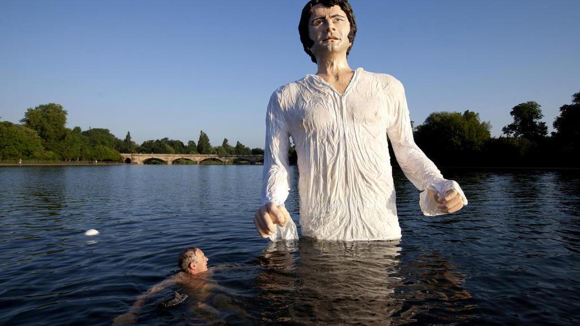 A swimmer approaches a statue meant to depict actor Colin Firth performing as Mr. Darcy, a character in Jane Austen's novel "Pride and Prejudice" at the Serpentine Lake, Hyde Park, London, on July 8, 2013.