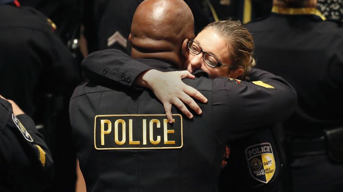 DART police officer Misty McBride, right, is embraced by a fellow officer as she arrives for a memorial at the Morton H. Meyerson Symphony Center on Tuesday in Dallas. Five police officers were killed and several injured, including McBride, during a shooting in downtown Dallas last Thursday night. Tensions between police officers and the black community have increased in the past week due to the shooting deaths of Alton Sterling, Philando Castile and Dallas police officers.