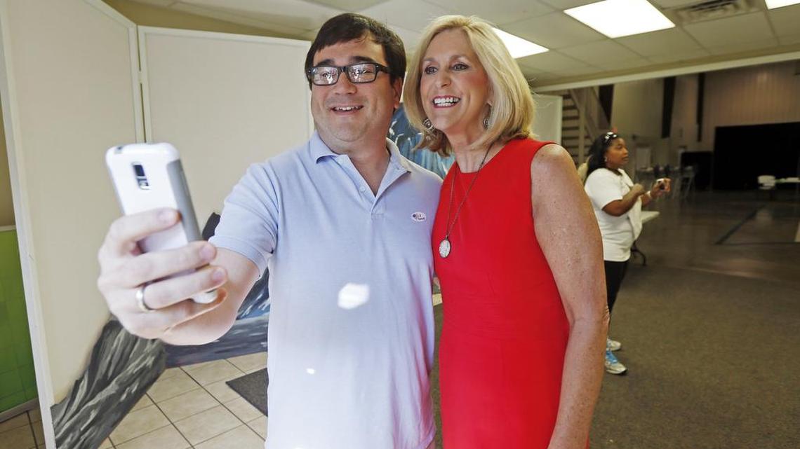 
Morgan Bondurant uses his smartphone to take a selfie of himself and state Treasurer Lynn Fitch as they exit the voting precinct after voting at the Highland Chapel Church in Madison, Miss., on Aug. 4. 
