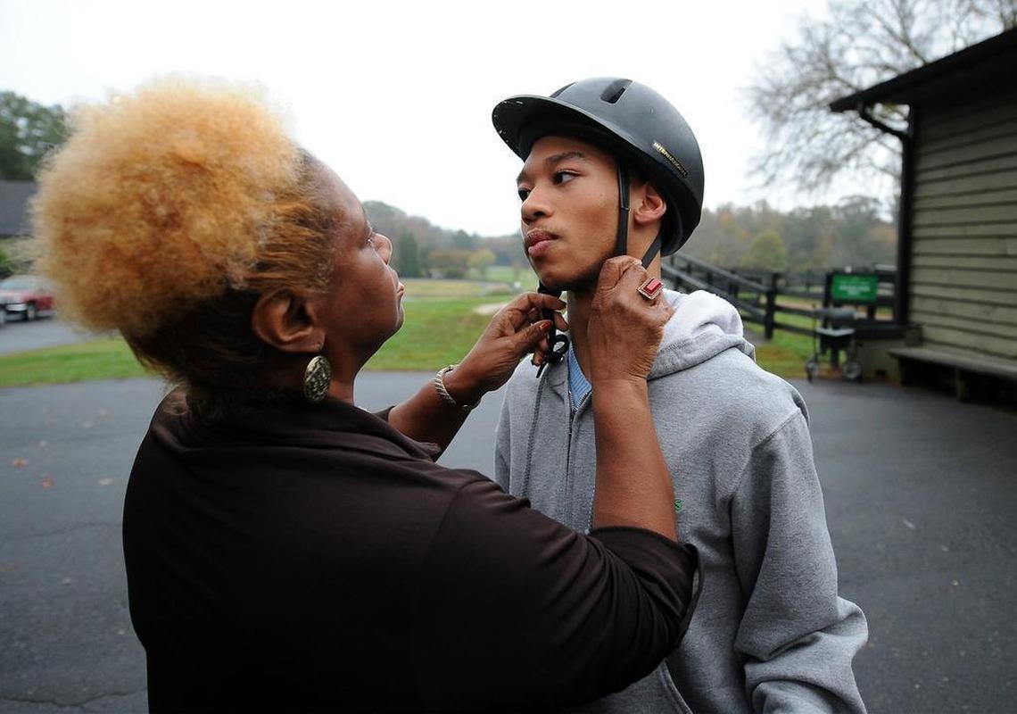 Saundra Adams, left, assists grandson Chancellor Lee Adams with his helmet before a horse ride in 2015. Chancellor, who has cerebral palsy and brain damage due to the traumatic circumstances of his birth, is now 18.