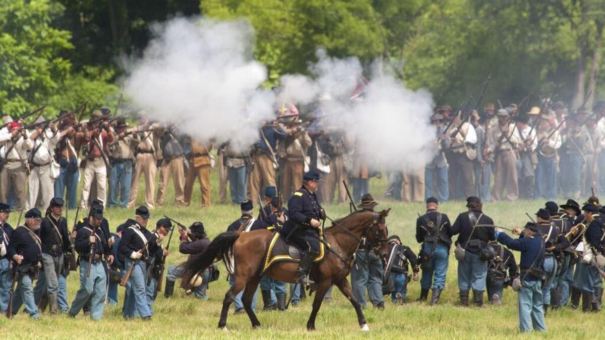 A line of Confederate soldiers re-enactors, rear, of Maj. General Henry Heth's troops, fire a volly towards re-enactors of Union General John Buford's cavalry unit, dismounted, during a re-enactment of the first day of battle during the 150th Gettysburg Anniversary National Civil War Battle Re-enactment on a farm outside Gettysburg on July 4, 2013.