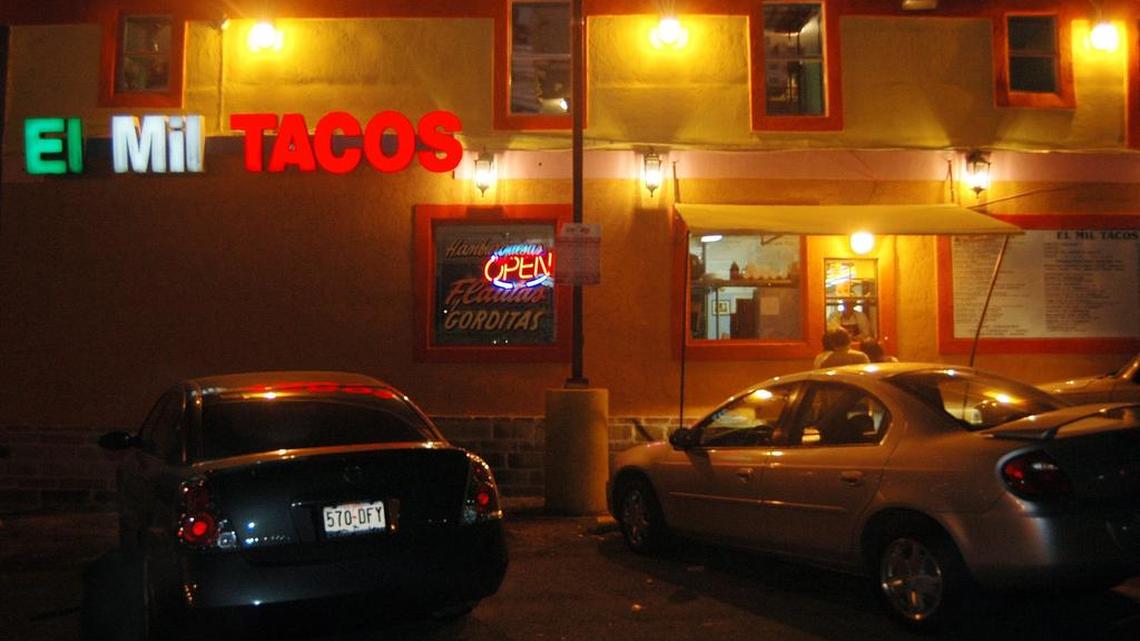 Neon and yellow lights light the parking lot and walk up window of El Mil Tacos on Hemphill St.