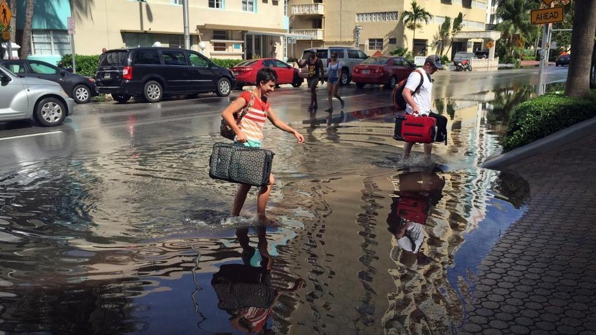 Oakley and Casey Jones, tourists from Idaho Falls, navigate the flooded streets of Miami Beach as they enter their hotel during last year’s king tide.