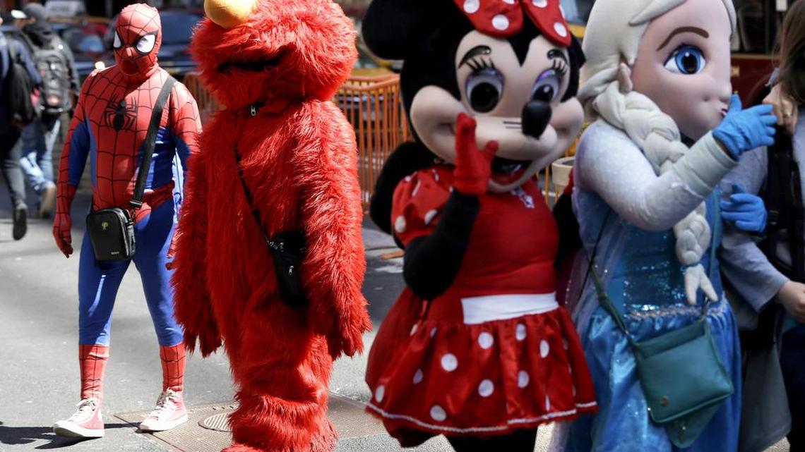 Costumed characters work for tips in New York's Times Square. Mayor Bill de Blasio has signed a bill that will regulate where and how costumed characters like Spider-Man and Elmo operate.