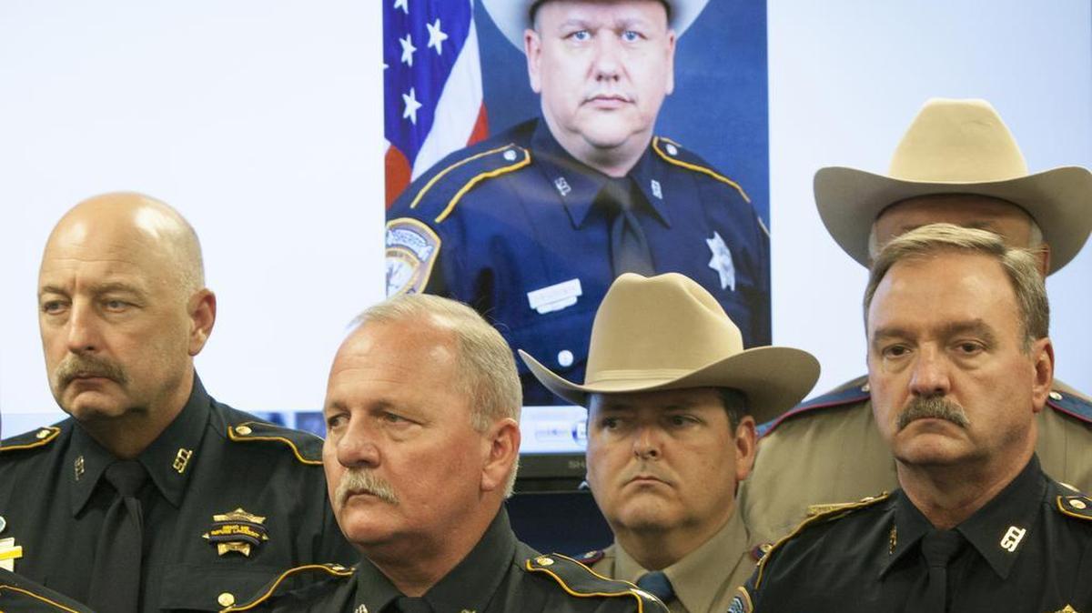 
Law enforcement officers attend a news conference regarding the shooting death of Harris County Sheriff’s Deputy Darren Goforth, pictured in back, on Saturday, Aug. 29, 2015, in Houston. Prosecutors on Saturday charged Shannon J. Miles with capital murder in the Friday killing of Goforth at a suburban Houston gas station. 
