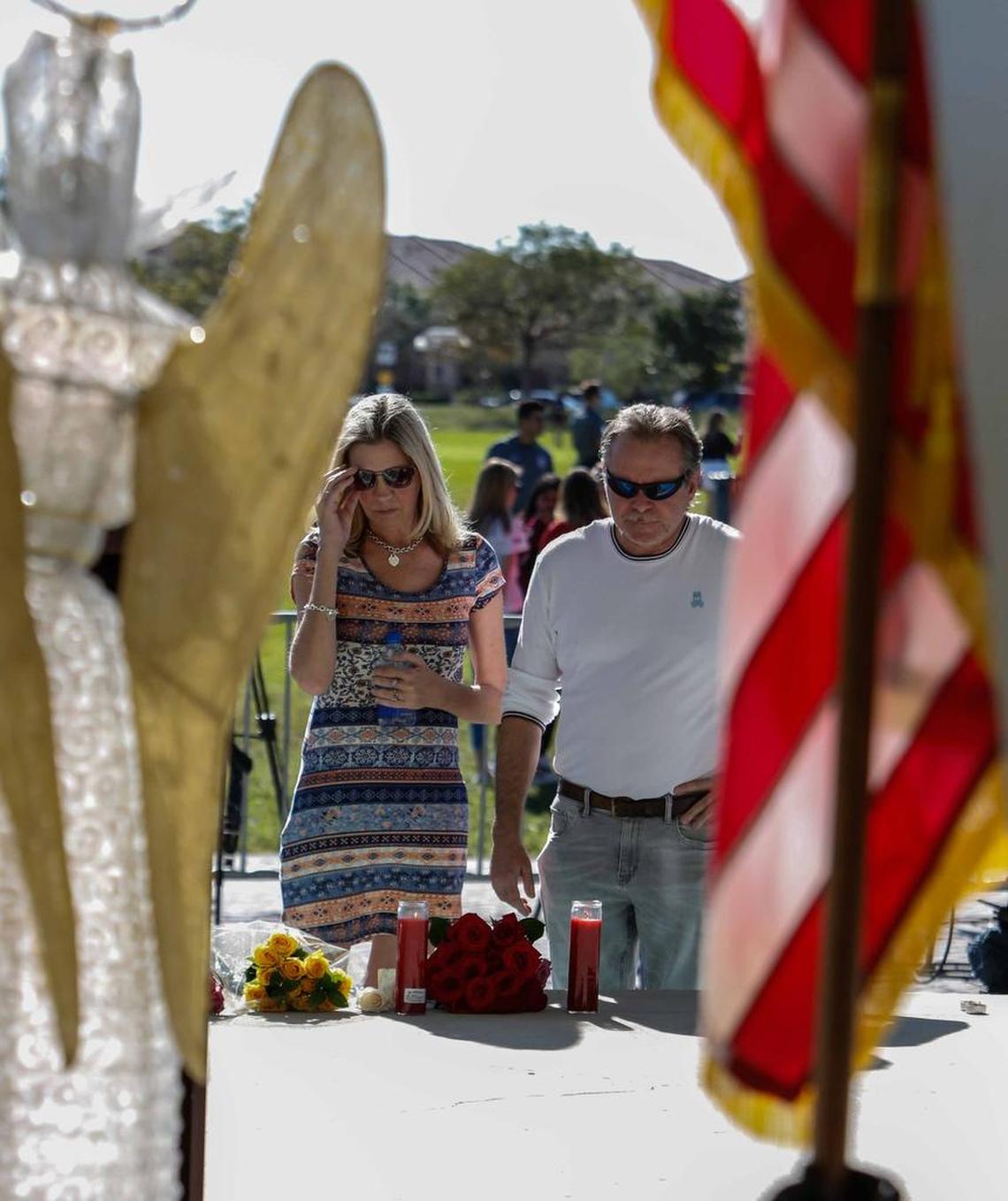 Jennifer Johnson and Max Furetta set down flowers before the start of the Parkland shooting vigil at Pine Trails Park Amphitheater on Thursday.