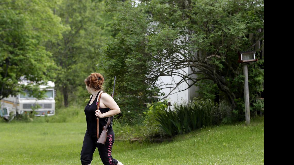 
Jennifer Hilchey-Reyell watches the tree line as she carries a .22 rifle walking from her mother's house to her own house near Dannemora, N.Y., Thursday. Hilchey-Reyell has been keeping a gun close at hand since the escape of two prisoners from the maximum-security Clinton Correctional Facility near her home.
