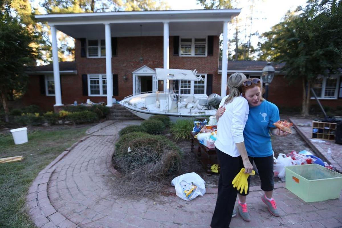 Beverly Steinhaus hugs Carol Hill, a friend who helped clean her house on Burwell Street after it was submerged in floodwater.