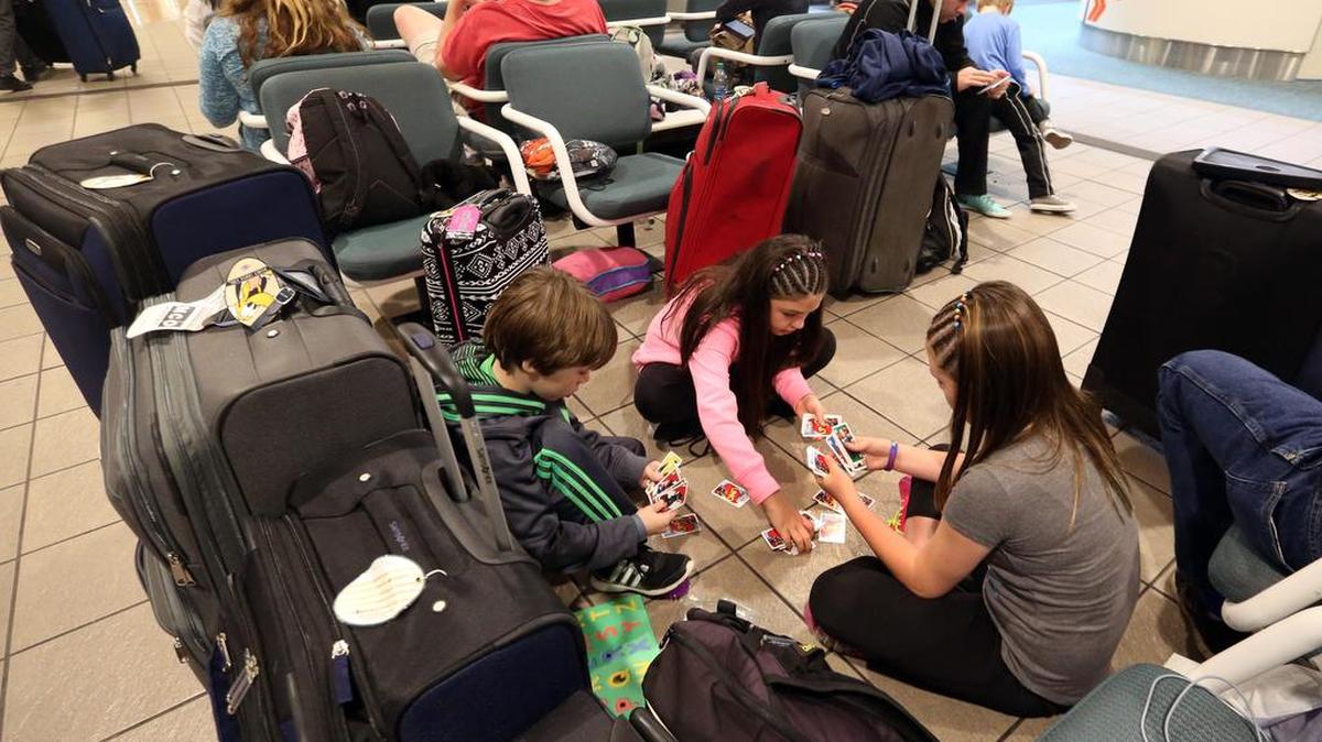 Liam Everett, 8, left, Chloe Betts,10, center, and Isabella Everett,10, of North Carolina, play a card game, Friday at Orlando International Airport in Orlanda, Fla. Both families flights were canceled due to winter weather in Raleigh, N.C. The two families are returning from a Disney cruise. Airlines have canceled more than 2,700 flights Friday to, from or within the U.S., as a blizzard swings up the East Coast, according to flight tracking service FlightAware.