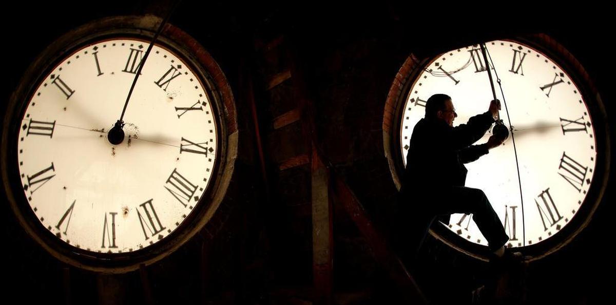 Custodian Ray Keen inspects a clock face before changing the time on the 100-year-old clock atop the Clay County Courthouse in Clay Center, Kan.