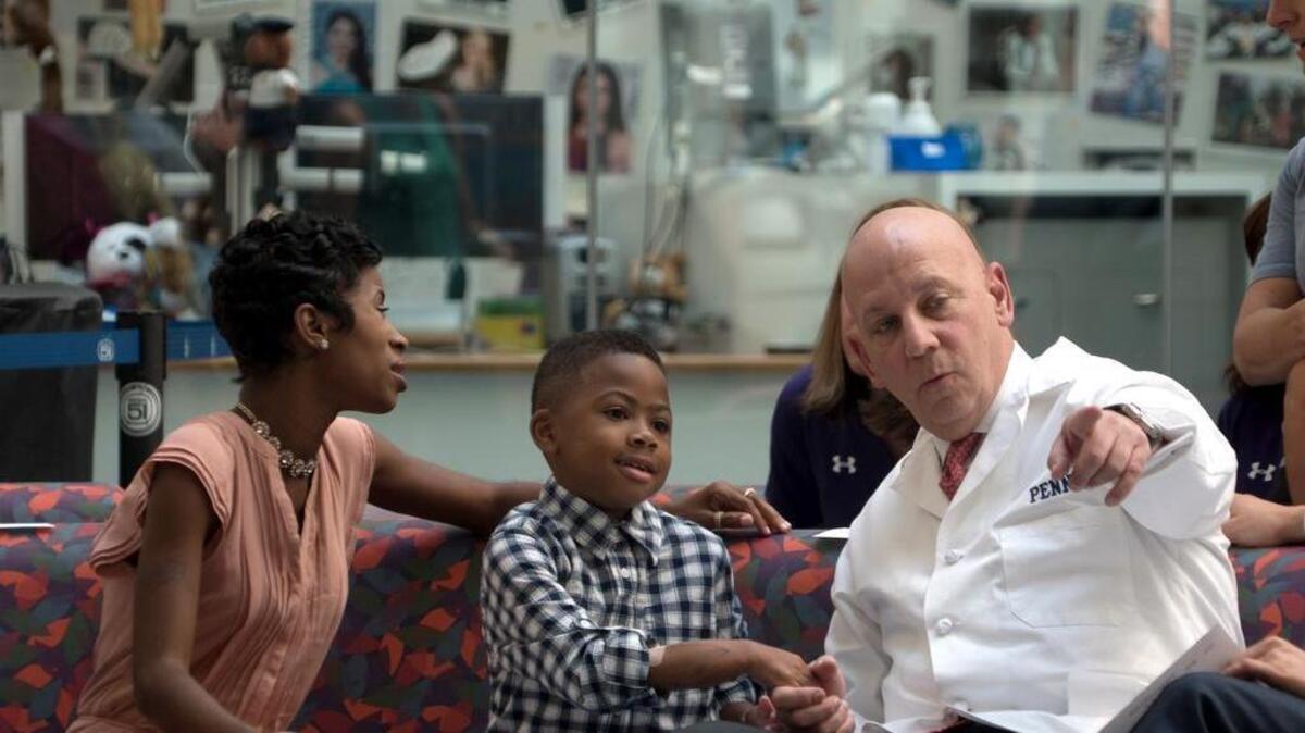 Zion Harvey, center, who received a double hand transplant in July 2015, sits next to his mother, Pattie Ray, left, and holds hands with one of his surgeons, L. Scott Levin, during a news conference Tuesday, Aug. 23, 2016, at The Children’s Hospital of Philadelphia. Zion talked about his progress since becoming the youngest hand transplant patient in the U.S.