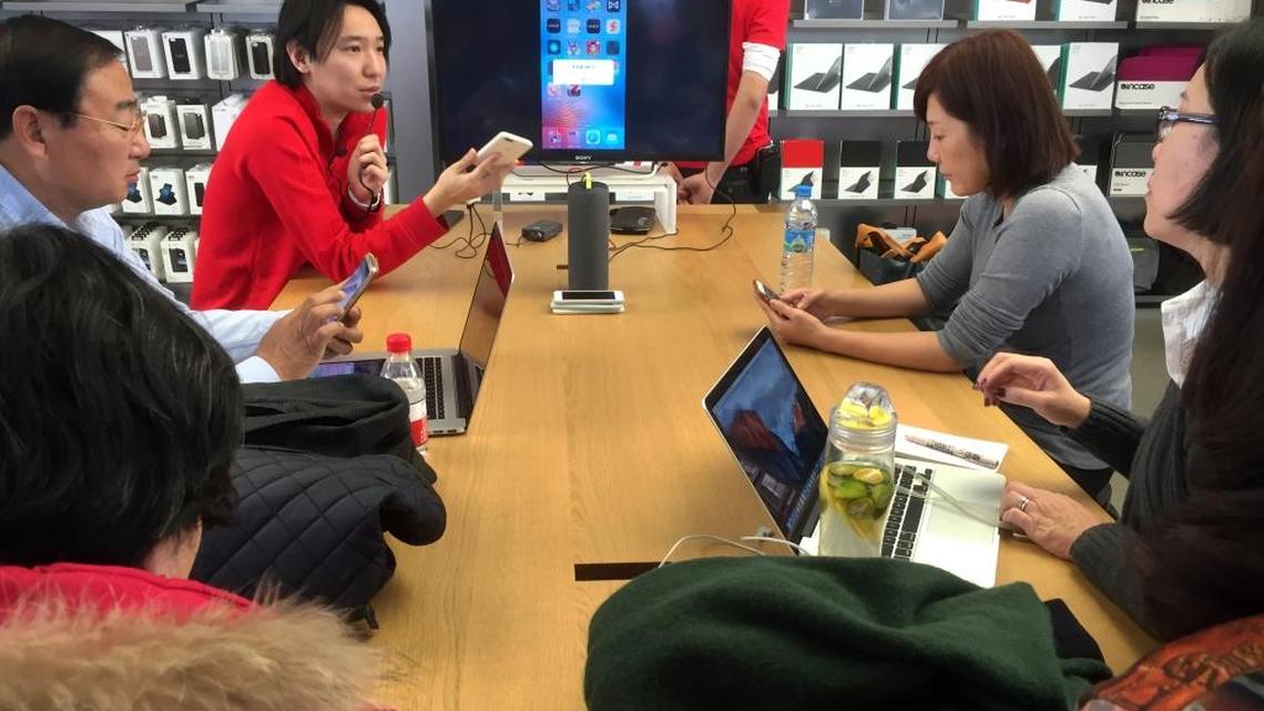 A employee gives customers a group lesson on using an iPhone at an Apple Store in Beijing, Thursday, the day Apple launched its smartphone-based payment system in China.
