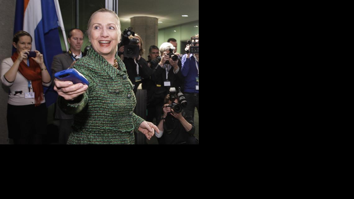
Then-U.S. Secretary of State Hillary Rodham Clinton hands off her mobile phone after arriving to meet with Dutch Foreign Minister Uri Rosenthal at the Ministry of Foreign Affairs in The Hague, Netherlands on Dec. 8, 2011. 

