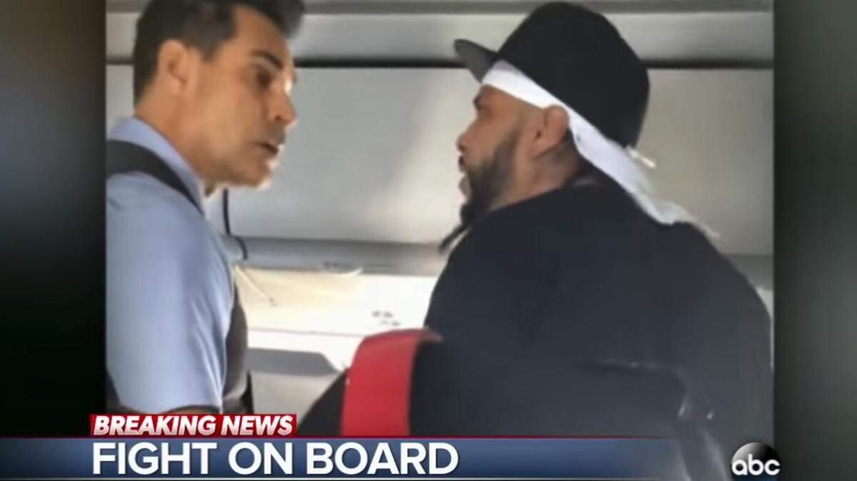 A flight attendant tries to calm a passenger on an American Airlines flight.