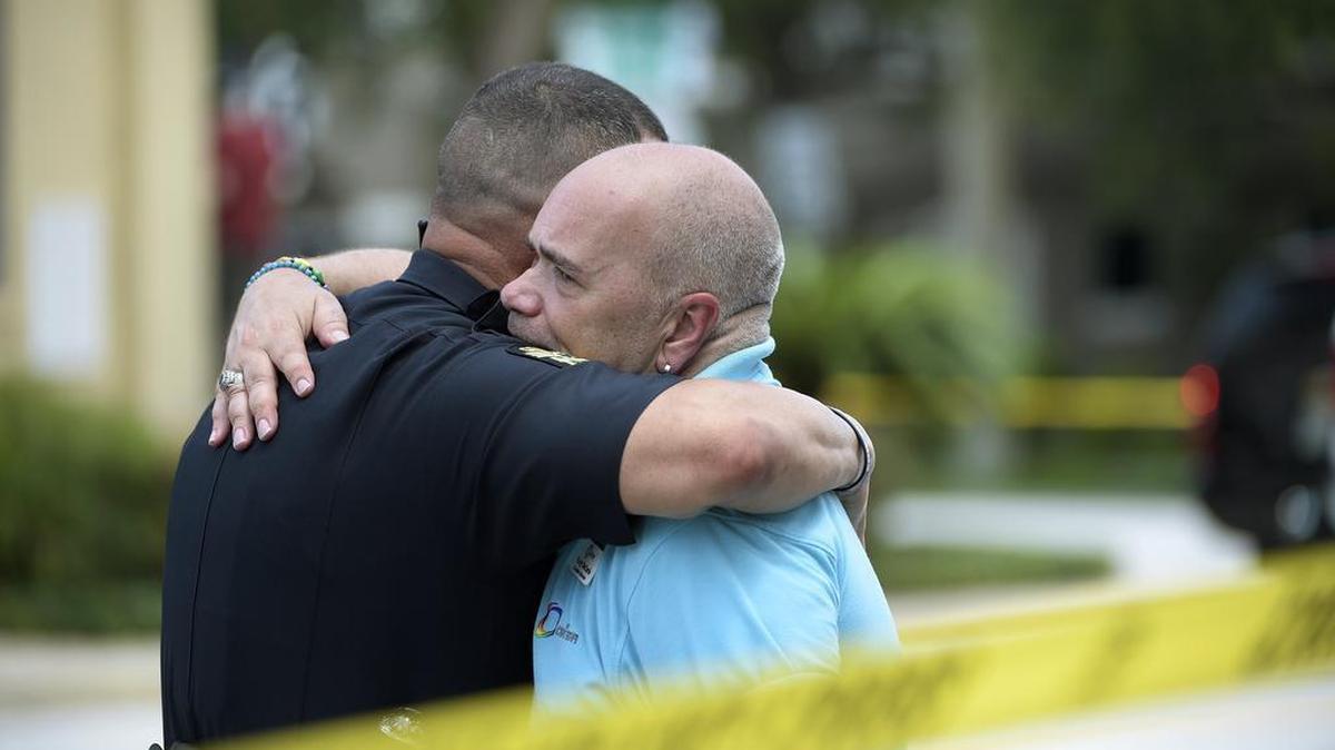 Terry DeCarlo, executive director of the LGBT Center of Central Florida, right, is comforted by an Orlando Police officer after a shooting involving multiple fatalities at a nightclub in Orlando, Fla., Sunday, June 12, 2016.
