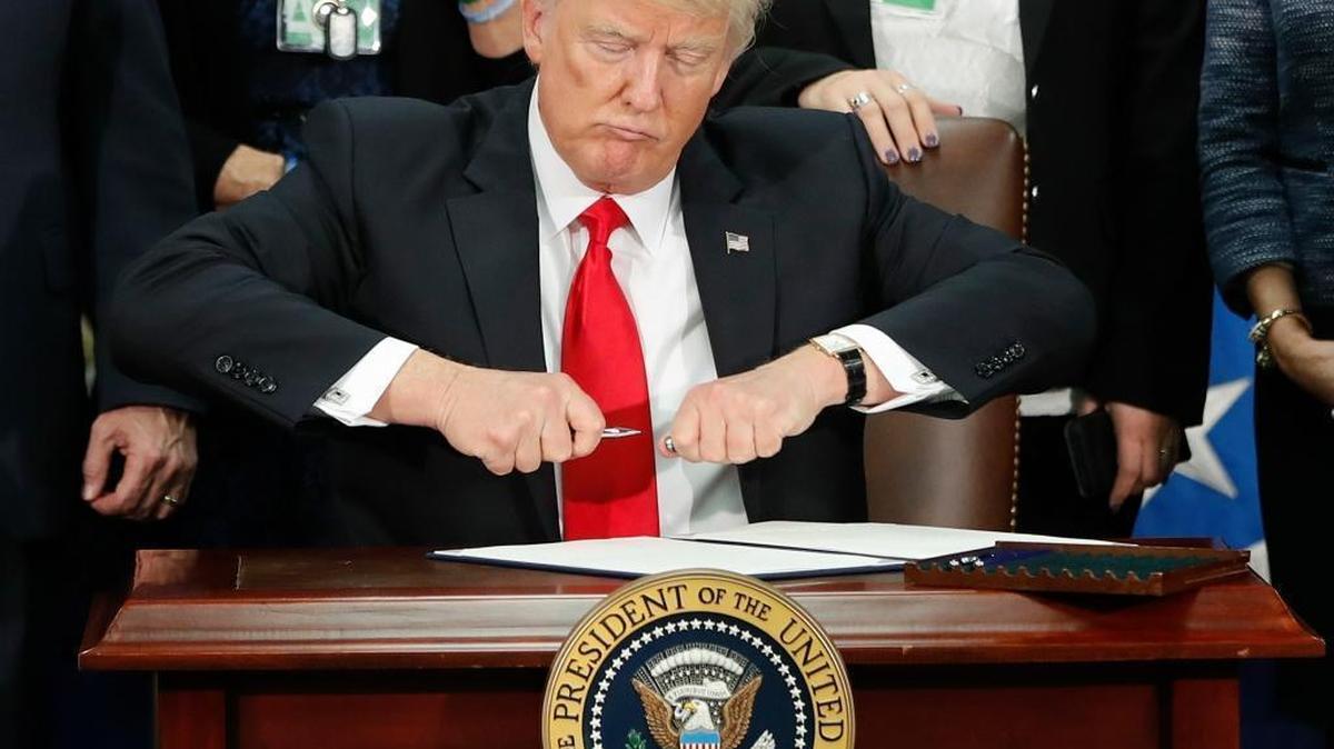 President Donald Trump takes the cap off a pen before signing executive order for immigration actions to build border wall during a visit to the Homeland Security Department in Washington, Wednesday, Jan. 25, 2017.