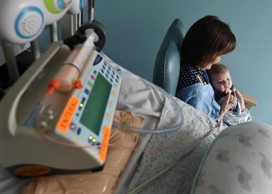 Valley Children’s Hospital volunteer cuddler Kerry Abbott cuddles Grant Early, nearly 4 months old, in the neonatal intensive care unit, as medical equipment he’s hooked up to sits nearby.