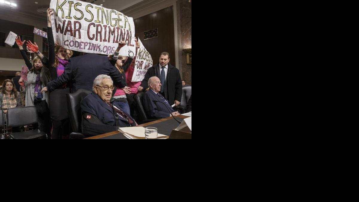
Protesters interrupt the start of a Senate Armed Services hearing as they shout at former Secretary of State Henry A. Kissinger, center, joined by former State Department head George P. Shultz, right, on Capitol Hill in Washington, Thursday, Jan. 29, 2015. The upheaval came as members of anti-war group Code Pink called the 91-year-old Kissinger a war criminal. 
